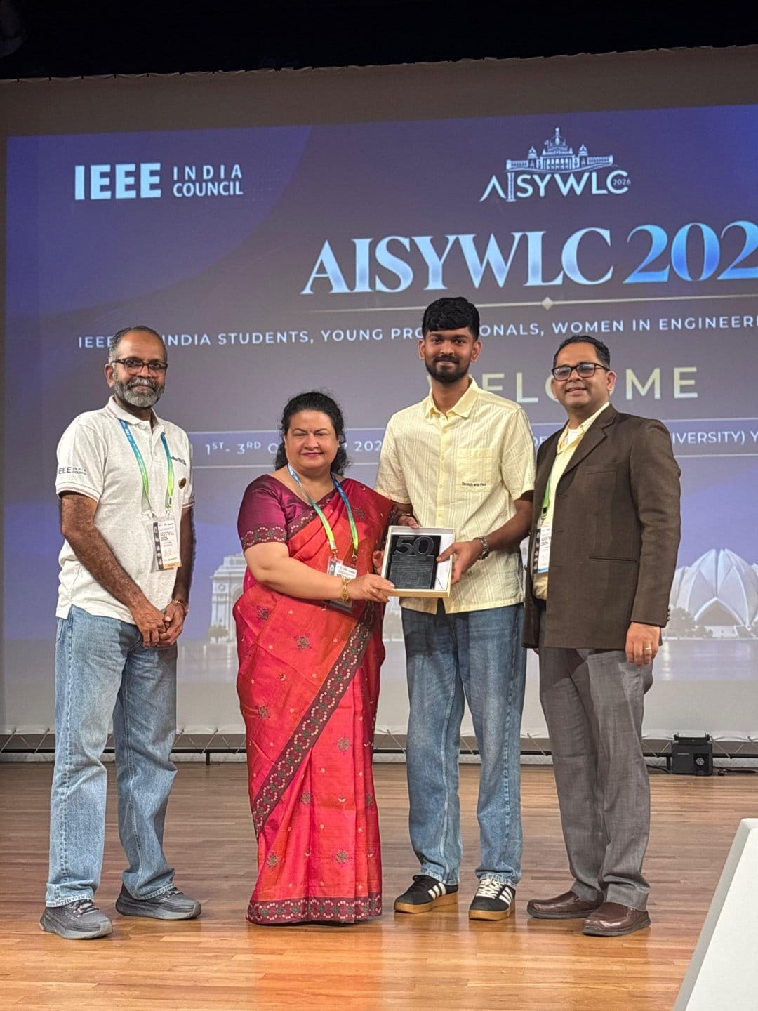 Gaurav Patil receiving an award plaque on stage at AISYWLC 2026